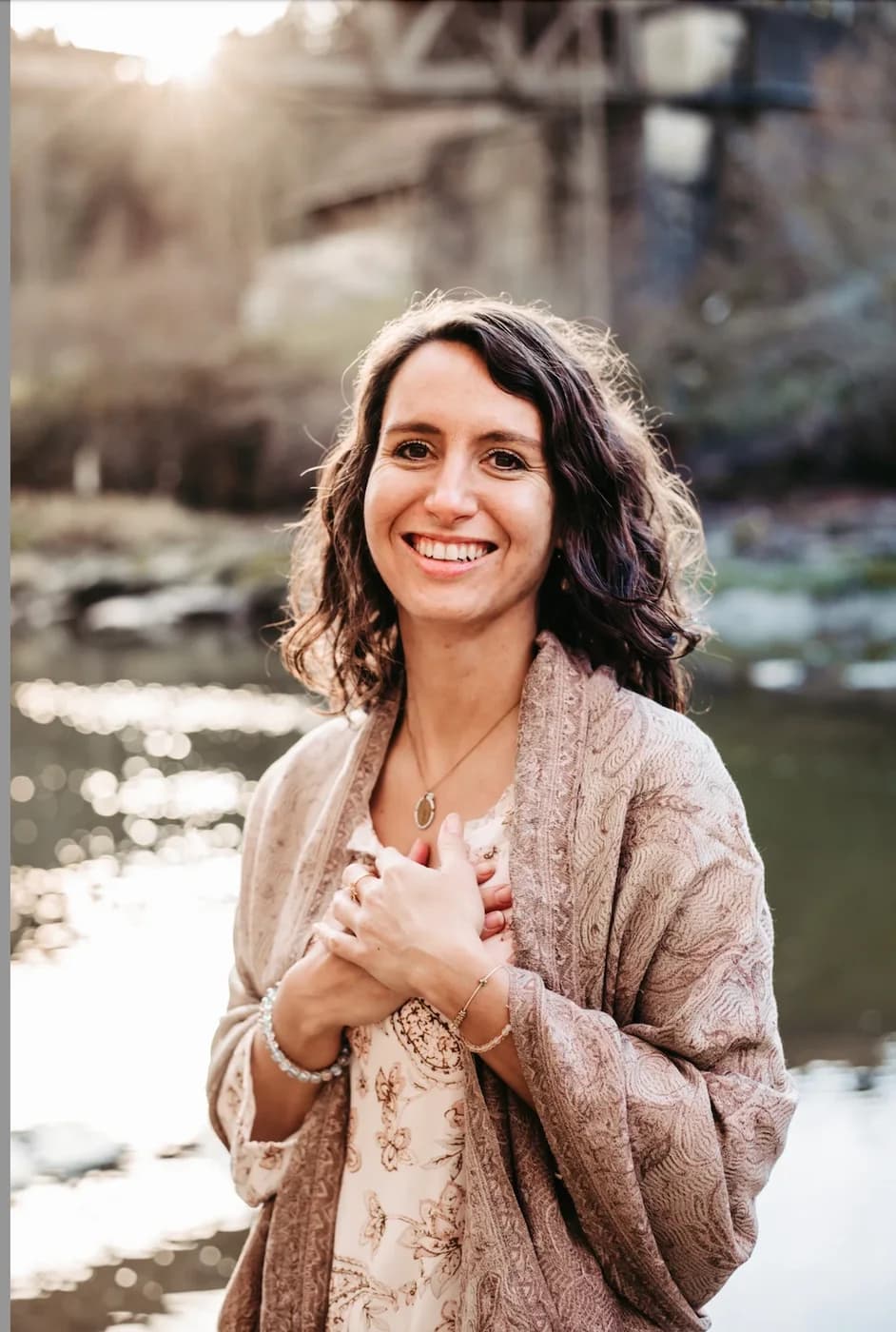 Cathrin Hauk im Freien an einem Fluss, die Hände vor der Brust gekreuzt.